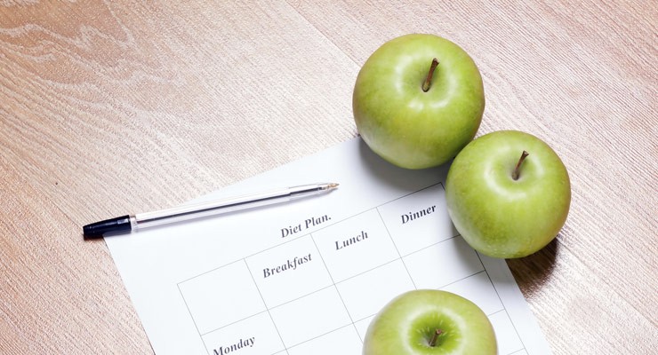 three apples on top of a chart next to a pen